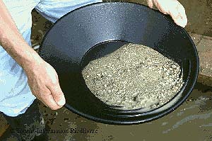 Die schweren Mineralkörner mit dem Gold bleiben am Boden der Goldwaschpfanne liegen